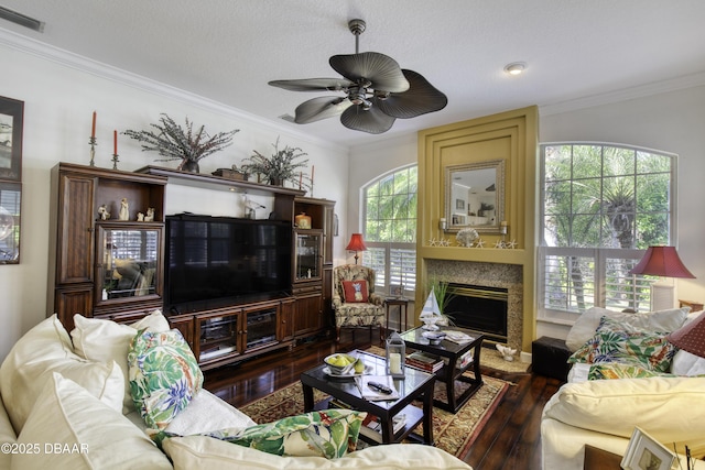 living area featuring visible vents, hardwood / wood-style flooring, a fireplace, crown molding, and ceiling fan