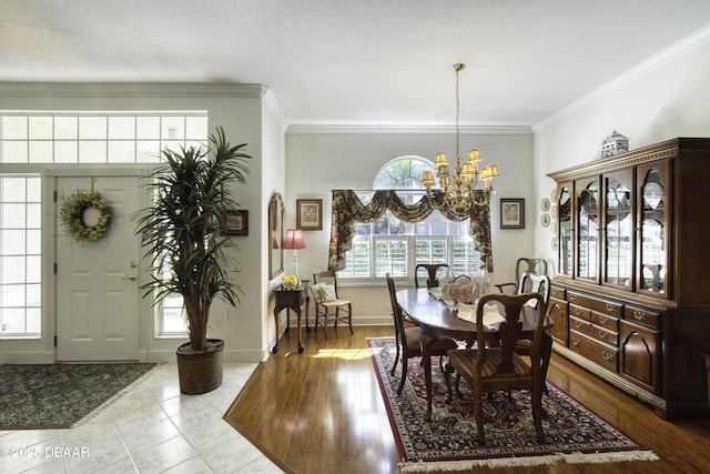 dining area featuring wood finished floors, baseboards, a textured ceiling, crown molding, and a notable chandelier