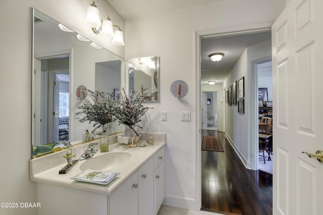 bathroom featuring vanity, wood finished floors, baseboards, and a textured ceiling