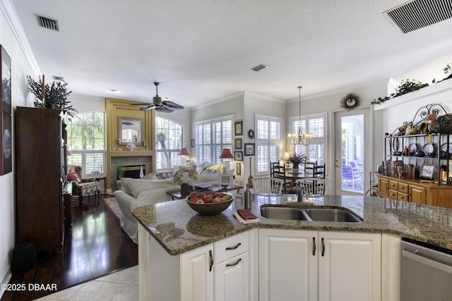 kitchen featuring visible vents, a sink, stainless steel dishwasher, crown molding, and ceiling fan with notable chandelier