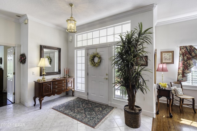 entrance foyer with ornamental molding, a textured ceiling, an inviting chandelier, light tile patterned floors, and baseboards