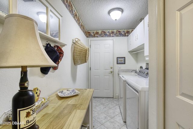 laundry room featuring washer and clothes dryer, cabinet space, and a textured ceiling