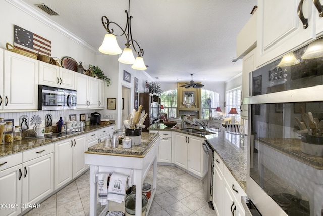 kitchen with visible vents, a sink, ceiling fan, ornamental molding, and stainless steel appliances