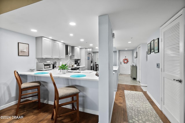4 Oceans W Blvd Unit 507D, Daytona Beach Shores, FL 32118 - kitchen featuring a breakfast bar, tasteful backsplash, appliances with stainless steel finishes, kitchen peninsula, and wall chimney range hood