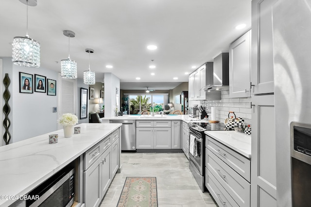 4 Oceans W Blvd Unit 507D, Daytona Beach Shores, FL 32118 - kitchen featuring appliances with stainless steel finishes, hanging light fixtures, light stone counters, decorative backsplash, and wall chimney exhaust hood