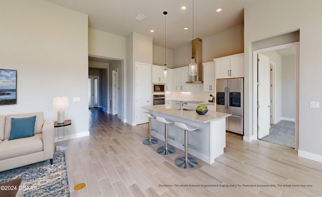 kitchen featuring light stone countertops, appliances with stainless steel finishes, decorative light fixtures, white cabinetry, and a breakfast bar area