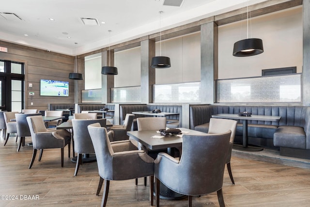 dining space with wooden walls and light hardwood / wood-style flooring