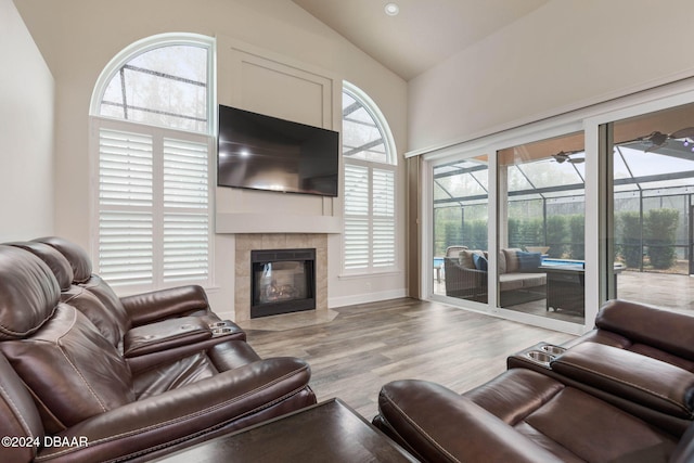 living room featuring a fireplace, light hardwood / wood-style flooring, vaulted ceiling, and a wealth of natural light