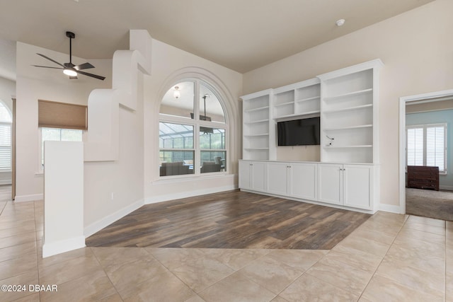 unfurnished living room with a wealth of natural light, light hardwood / wood-style flooring, ceiling fan, and built in features