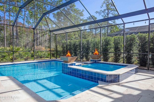 view of pool with a fire pit, glass enclosure, and a patio area