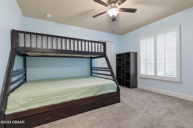 bedroom with ceiling fan, light colored carpet, and a textured ceiling