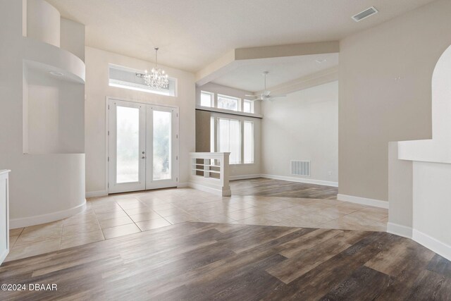 entryway featuring french doors, ceiling fan with notable chandelier, and light hardwood / wood-style flooring