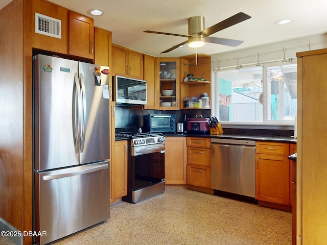 650 S Pine St, New Smyrna Beach, FL 32169 - kitchen with stainless steel appliances, ceiling fan, visible vents, and brown cabinetry