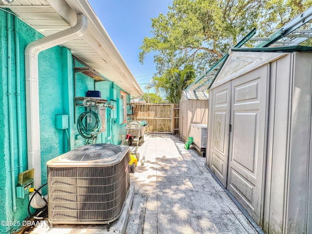 650 S Pine St, New Smyrna Beach, FL 32169 - view of patio / terrace with fence, a storage unit, central AC unit, and an outbuilding