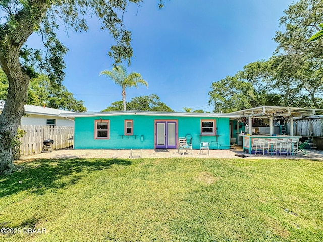 650 S Pine St, New Smyrna Beach, FL 32169 - back of property with fence, outdoor dry bar, a yard, and a patio area