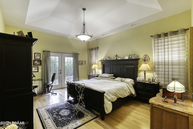 bedroom with a raised ceiling, access to exterior, french doors, and light hardwood / wood-style floors