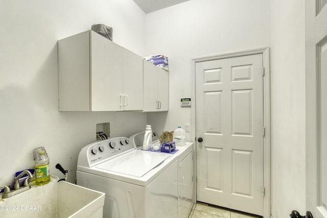 clothes washing area featuring cabinets, sink, light tile patterned flooring, and washer and dryer