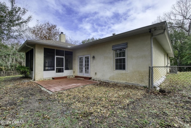 back of property with a sunroom, a patio area, and french doors