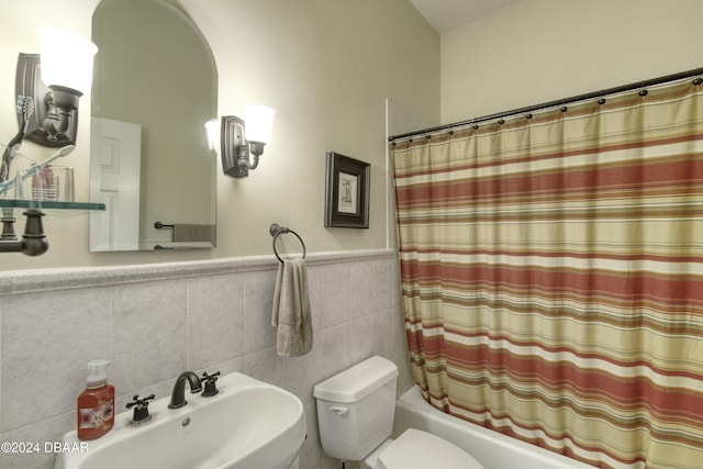 full bathroom featuring toilet, tile walls, shower / bath combo with shower curtain, and sink