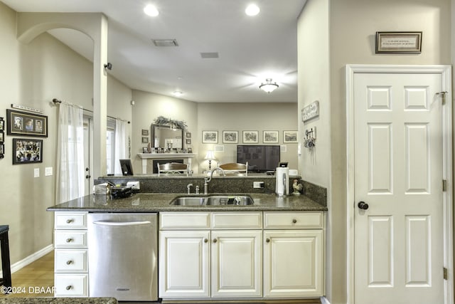 kitchen featuring sink, wood-type flooring, dark stone countertops, dishwasher, and white cabinetry