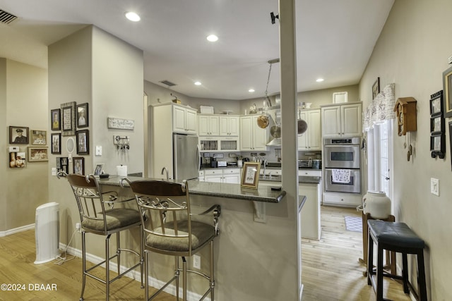 kitchen featuring a kitchen bar, appliances with stainless steel finishes, and light hardwood / wood-style floors