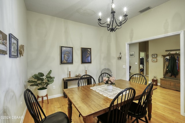 dining space with light hardwood / wood-style floors and a chandelier