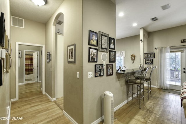 corridor featuring a high ceiling and light hardwood / wood-style flooring