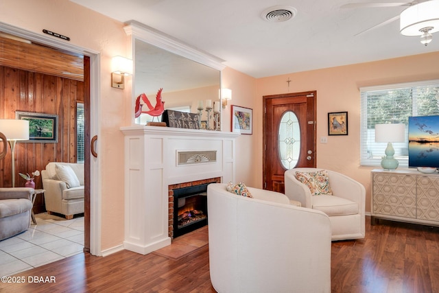 living room featuring hardwood / wood-style flooring, wood walls, and ceiling fan