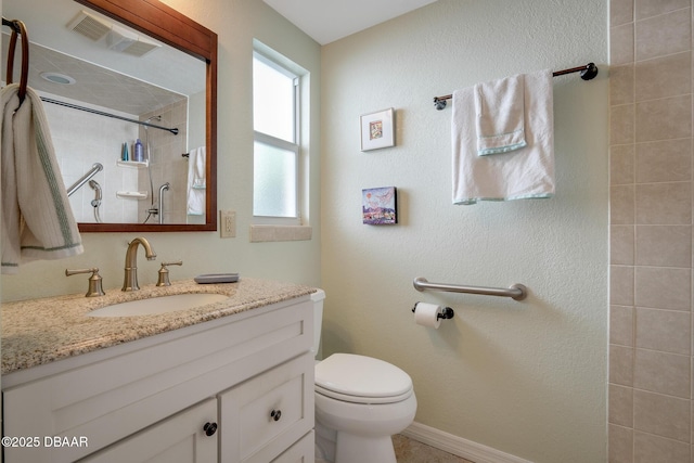 bathroom featuring toilet, a tile shower, and vanity