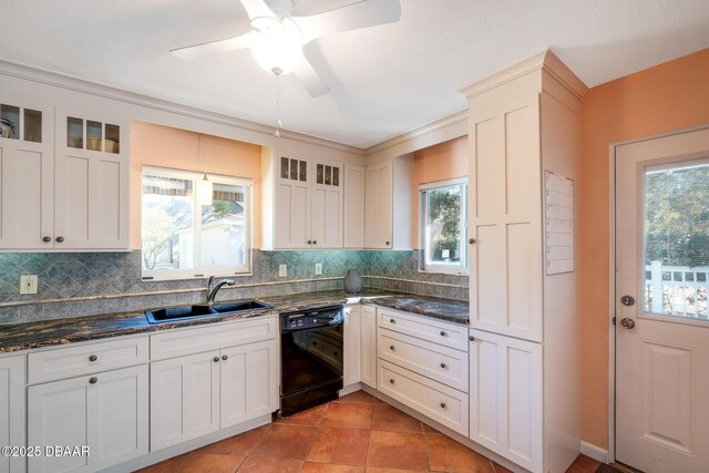 kitchen featuring a healthy amount of sunlight, dishwasher, dark stone counters, and sink