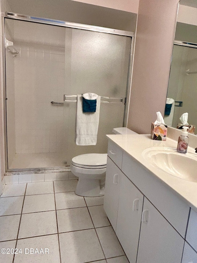 bathroom with tile patterned floors, a shower with door, vanity, and toilet