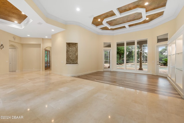 empty room featuring a towering ceiling, ornamental molding, light wood-type flooring, and coffered ceiling