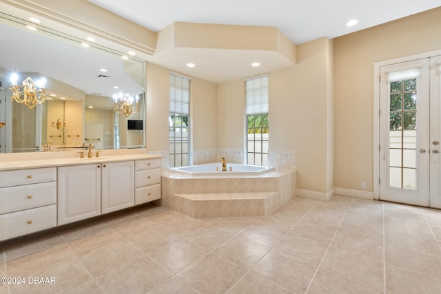 bathroom featuring a chandelier, vanity, tile patterned floors, and tiled tub