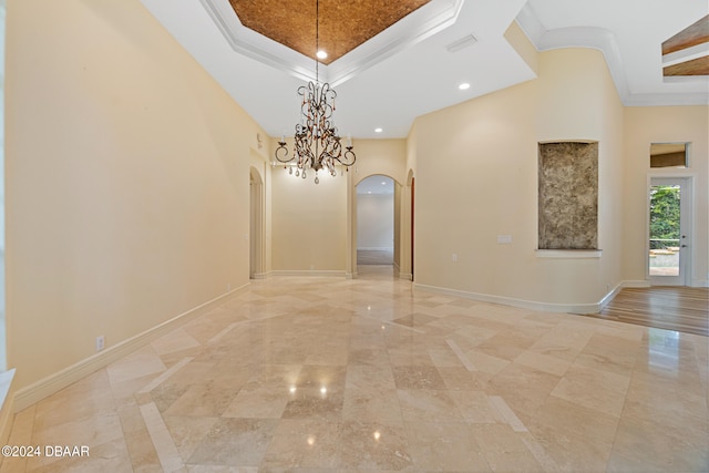 empty room with a high ceiling, an inviting chandelier, and crown molding