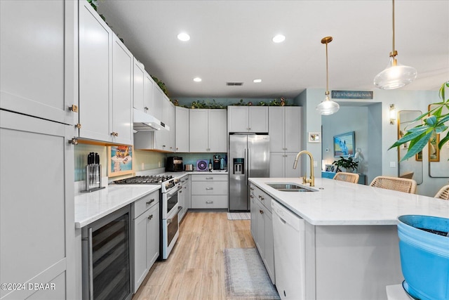 kitchen with pendant lighting, sink, a breakfast bar, beverage cooler, and white appliances