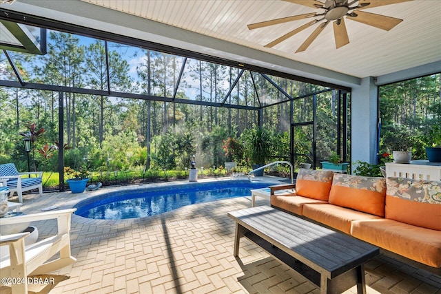 view of pool with glass enclosure, outdoor lounge area, a patio, and ceiling fan