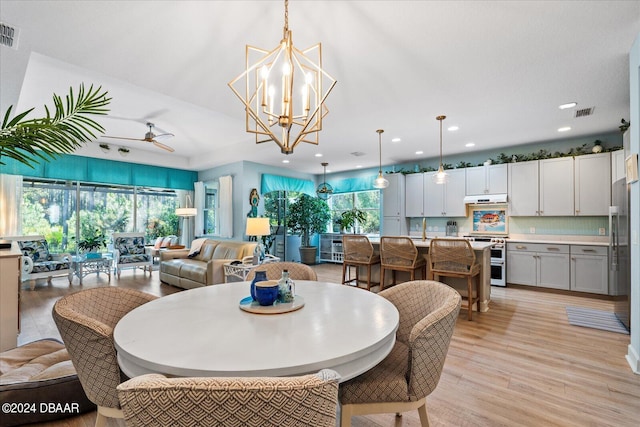 dining area featuring ceiling fan with notable chandelier and light hardwood / wood-style flooring