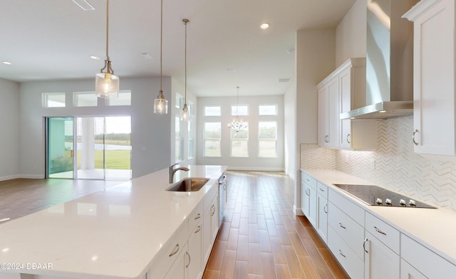 kitchen with pendant lighting, plenty of natural light, a spacious island, and wall chimney range hood