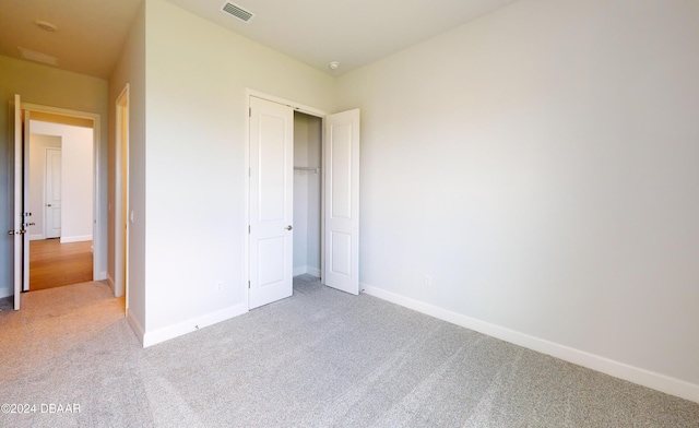 unfurnished bedroom featuring light colored carpet and a closet