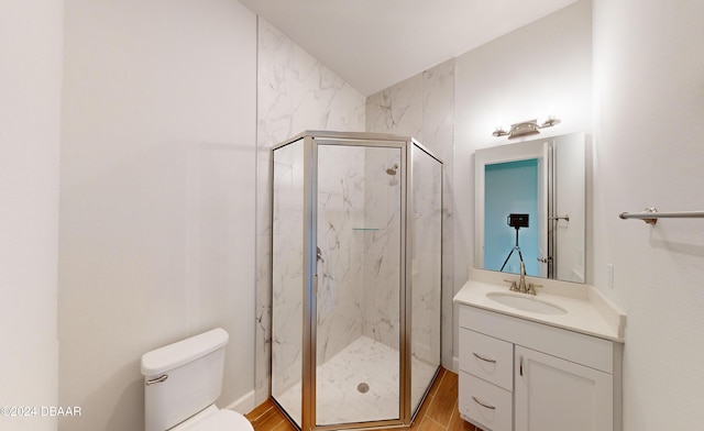 bathroom with hardwood / wood-style flooring, toilet, vanity, and walk in shower