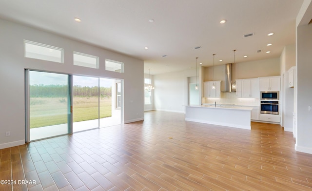 unfurnished living room with light hardwood / wood-style floors, an inviting chandelier, and sink