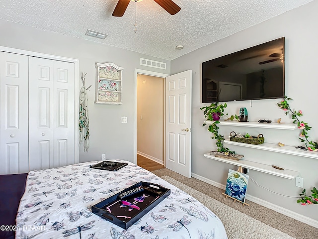 bedroom with ceiling fan, a textured ceiling, a closet, and carpet