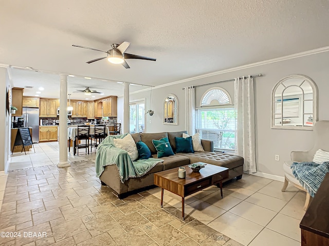 living room with ceiling fan, a textured ceiling, crown molding, and decorative columns