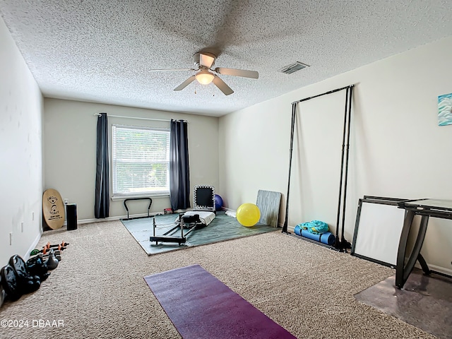 exercise room featuring a textured ceiling, carpet flooring, and ceiling fan