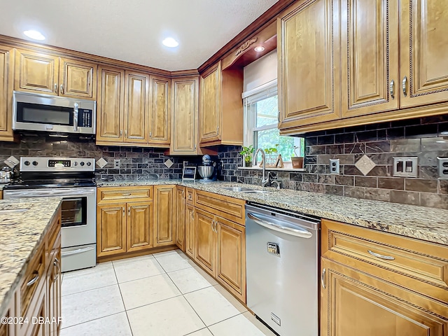 kitchen featuring light stone countertops, appliances with stainless steel finishes, sink, and light tile patterned floors