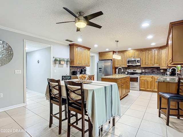 kitchen with a center island with sink, tasteful backsplash, ceiling fan, appliances with stainless steel finishes, and decorative light fixtures