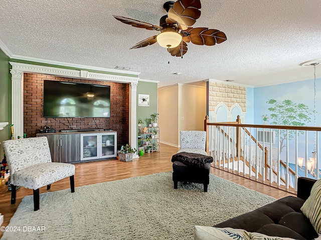 living room featuring a textured ceiling, hardwood / wood-style flooring, ceiling fan, crown molding, and a fireplace