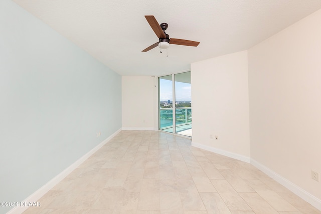 unfurnished room with a textured ceiling, a wall of windows, and ceiling fan