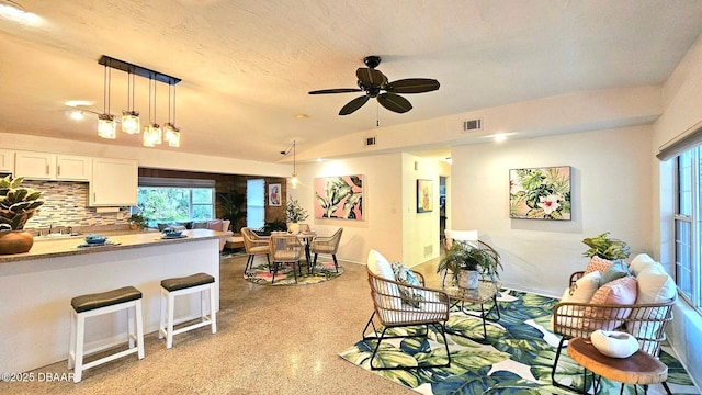 interior space with lofted ceiling, a healthy amount of sunlight, a textured ceiling, and ceiling fan