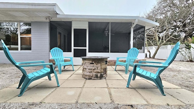 view of patio featuring an outdoor fire pit and a sunroom